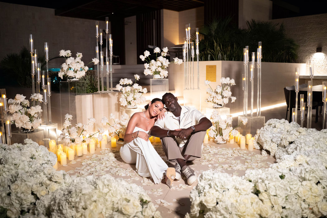 Couple sitting amidst white flowers and candles