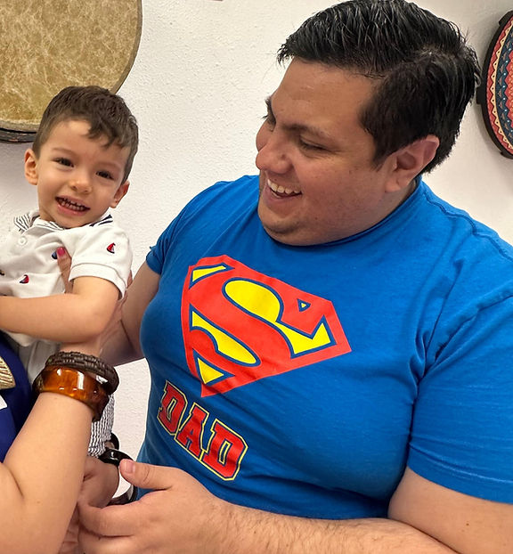 Luka and his dad Luis, smiling in their bilingual parent-child music class at Mi Casa Es Tu Casa in Austin, TX.