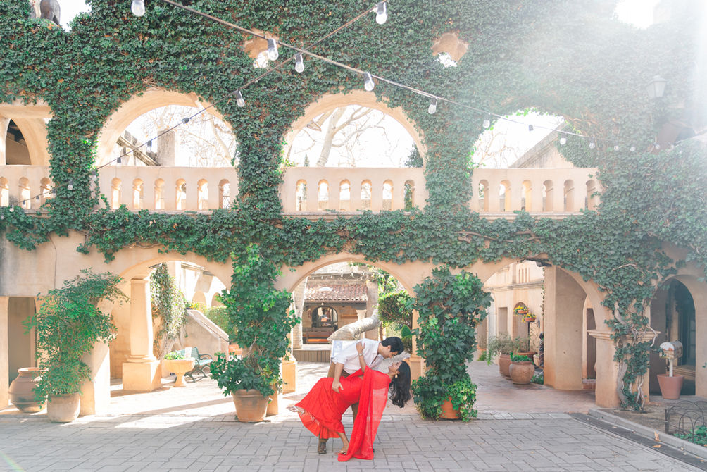 Candid moment of a bride and groom standing under the arched stone corridors of a historic Spanish-style villa at Tlaquepaque Center in Sedona, Arizona.