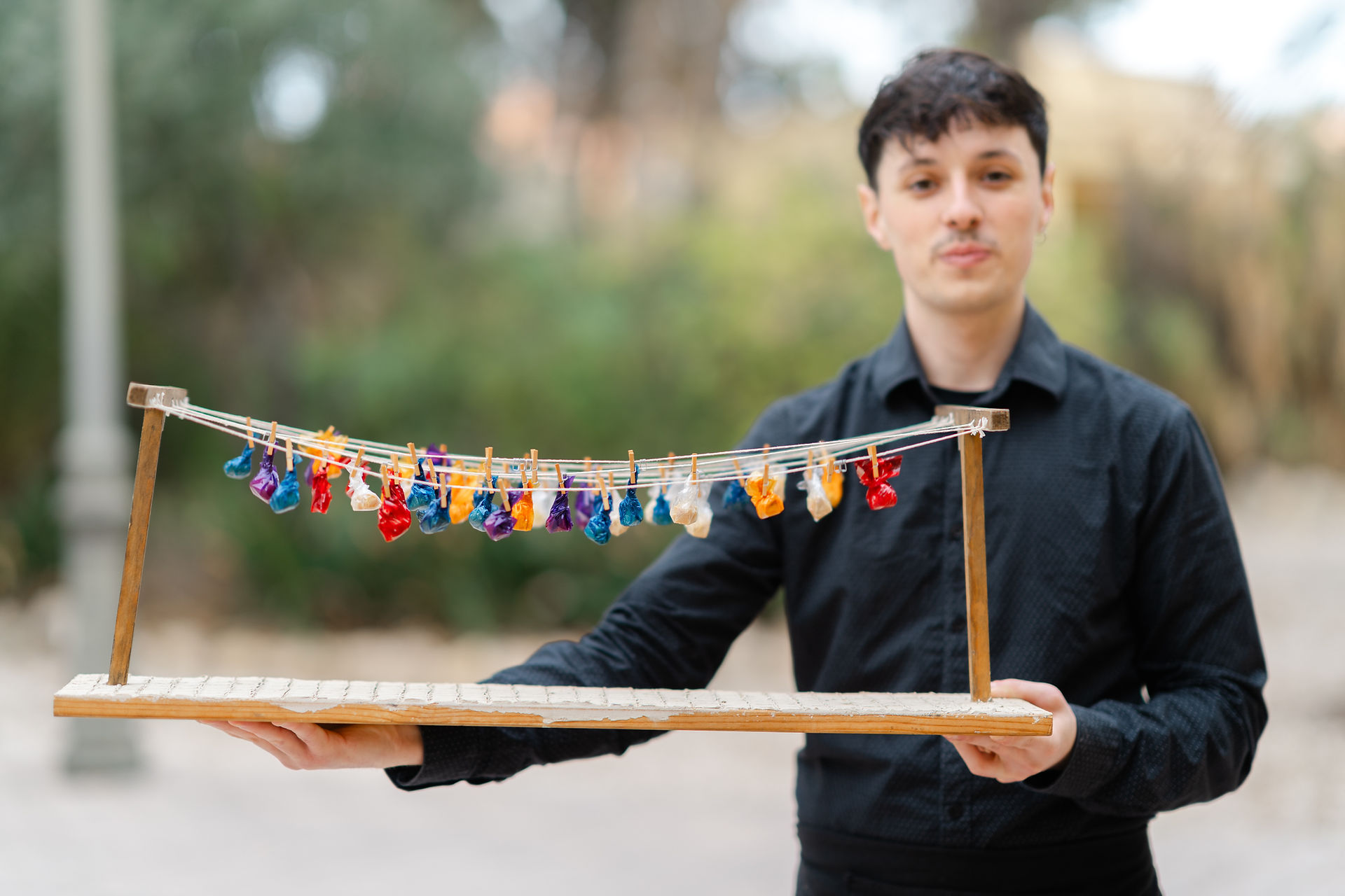 A server presenting a unique display of colorful appetizers hanging from a wooden frame at a Finca De Torre Bosch wedding in Alicante.