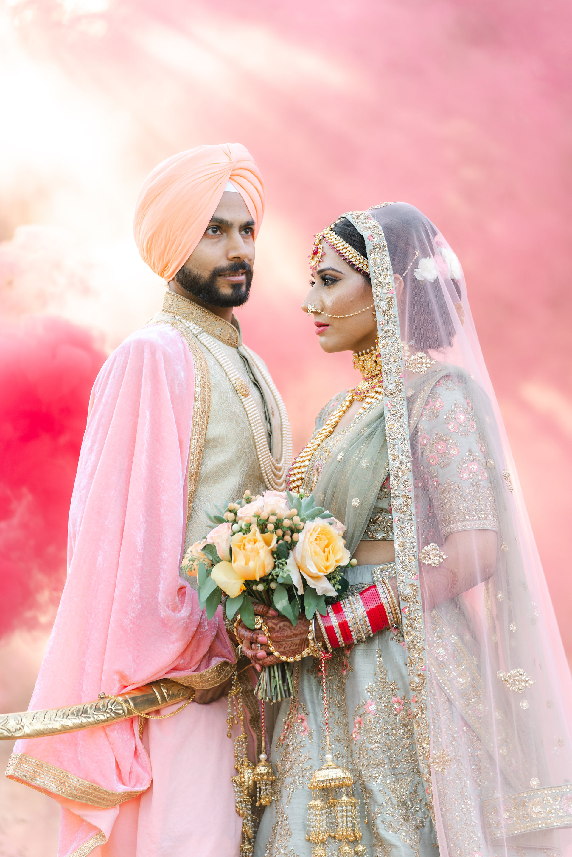 A close-up profile portrait of a South Asian bride and groom looking at each other, highlighting intricate bridal jewelry and cultural wedding attire.