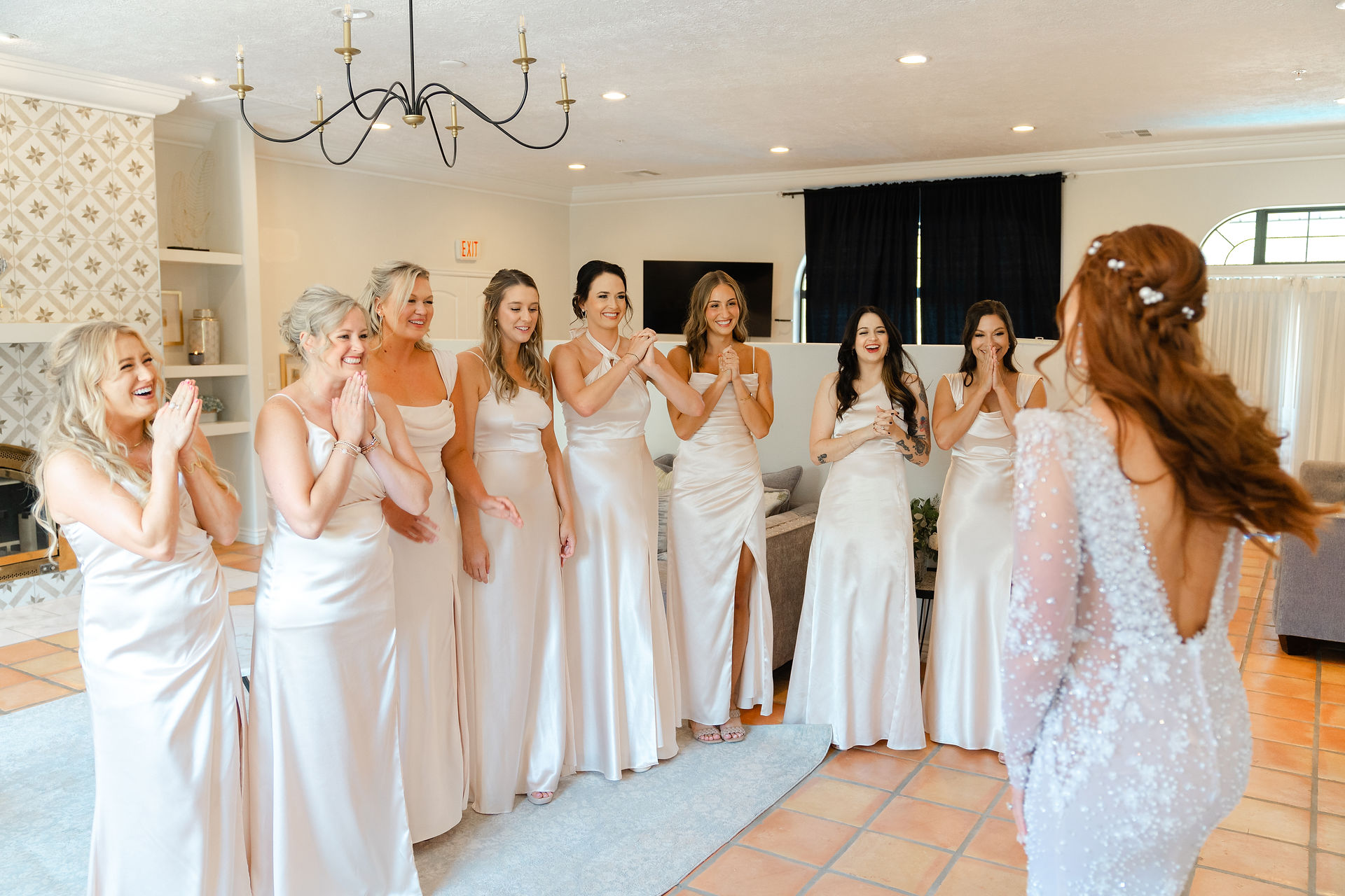 A joyful first look moment as a group of bridesmaids in matching white dresses cheer and react with excitement to the bride in her gown at a Zion National Park Wedding.