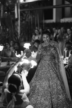A black and white candid portrait of a South Asian bride smiling and dancing during her wedding rece
