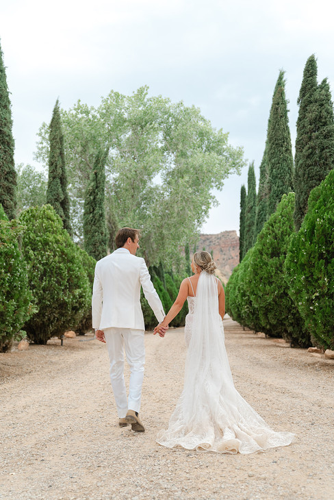 The bride and groom walking hand-in-hand toward the elegant Zion Red Rock Villa during their Zion National Park wedding.