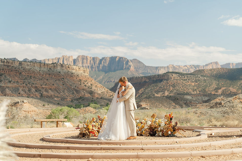 Adventure wedding bride and groom posing on a rocky ridge with the iconic red rock peaks of Zion National Park in the background.