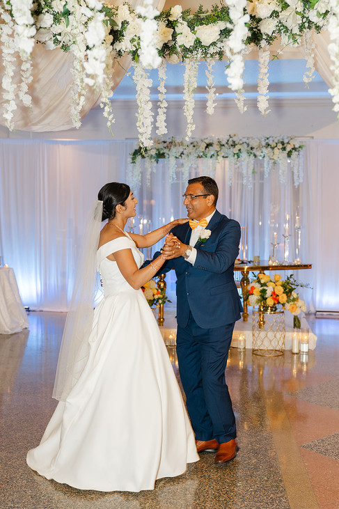 Bride Sarah in her white wedding gown sharing a joyful dance with her father in the decorated ballroom at Norwood Hills Country Club.