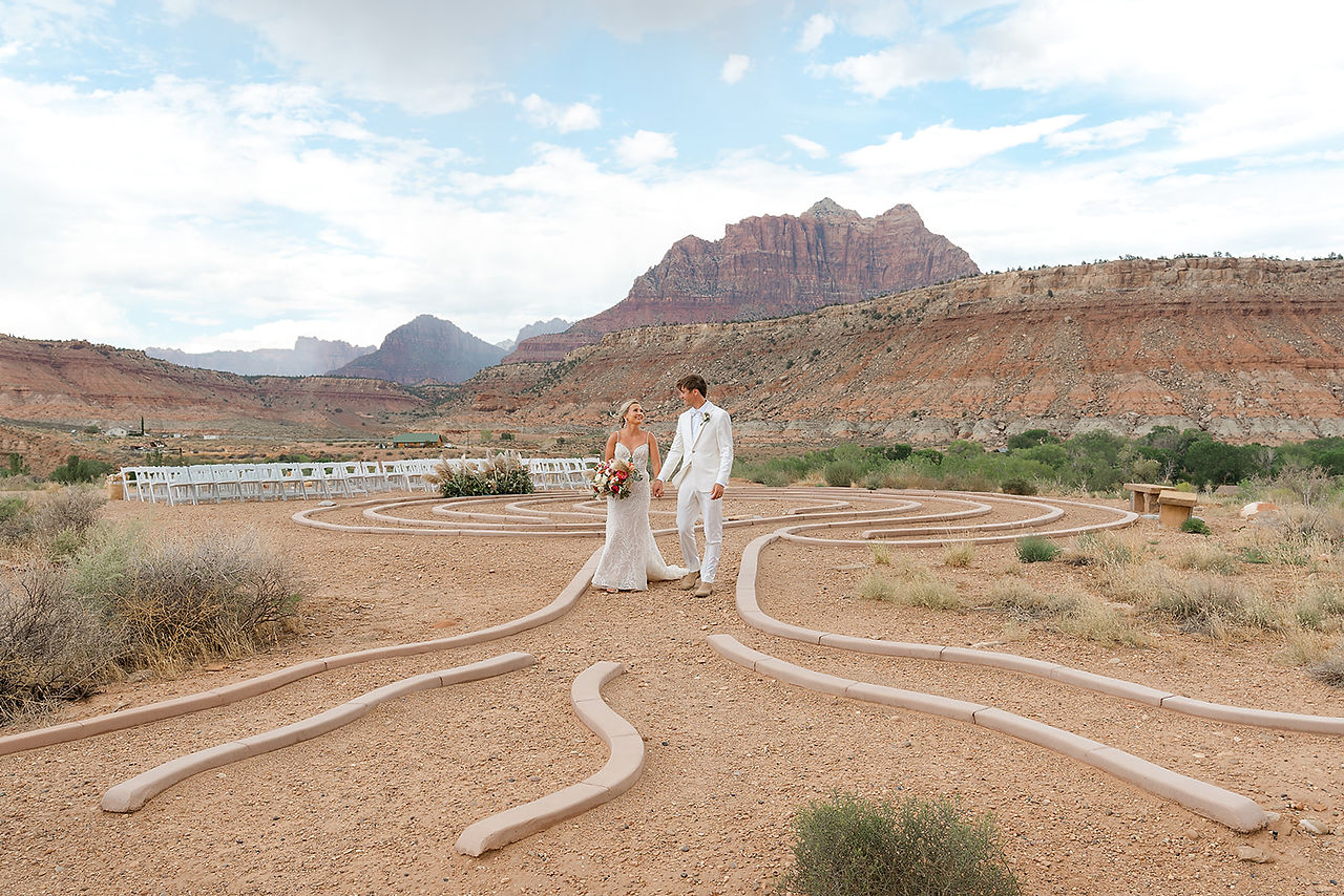 A wide-angle shot of the bride and groom standing at the center of the stone labyrinth for their Zion National Park wedding.