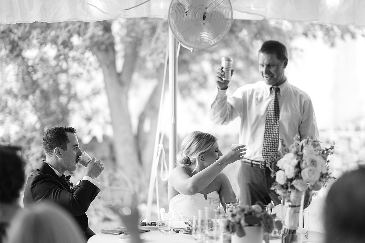 A wedding guest raising a glass for a toast at an outdoor Colorado Trading Post wedding reception.