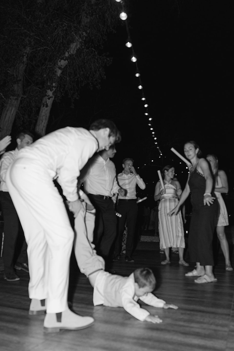 A candid black and white photo of the groom playing with a young child on the dance floor at a Zion National Park wedding.