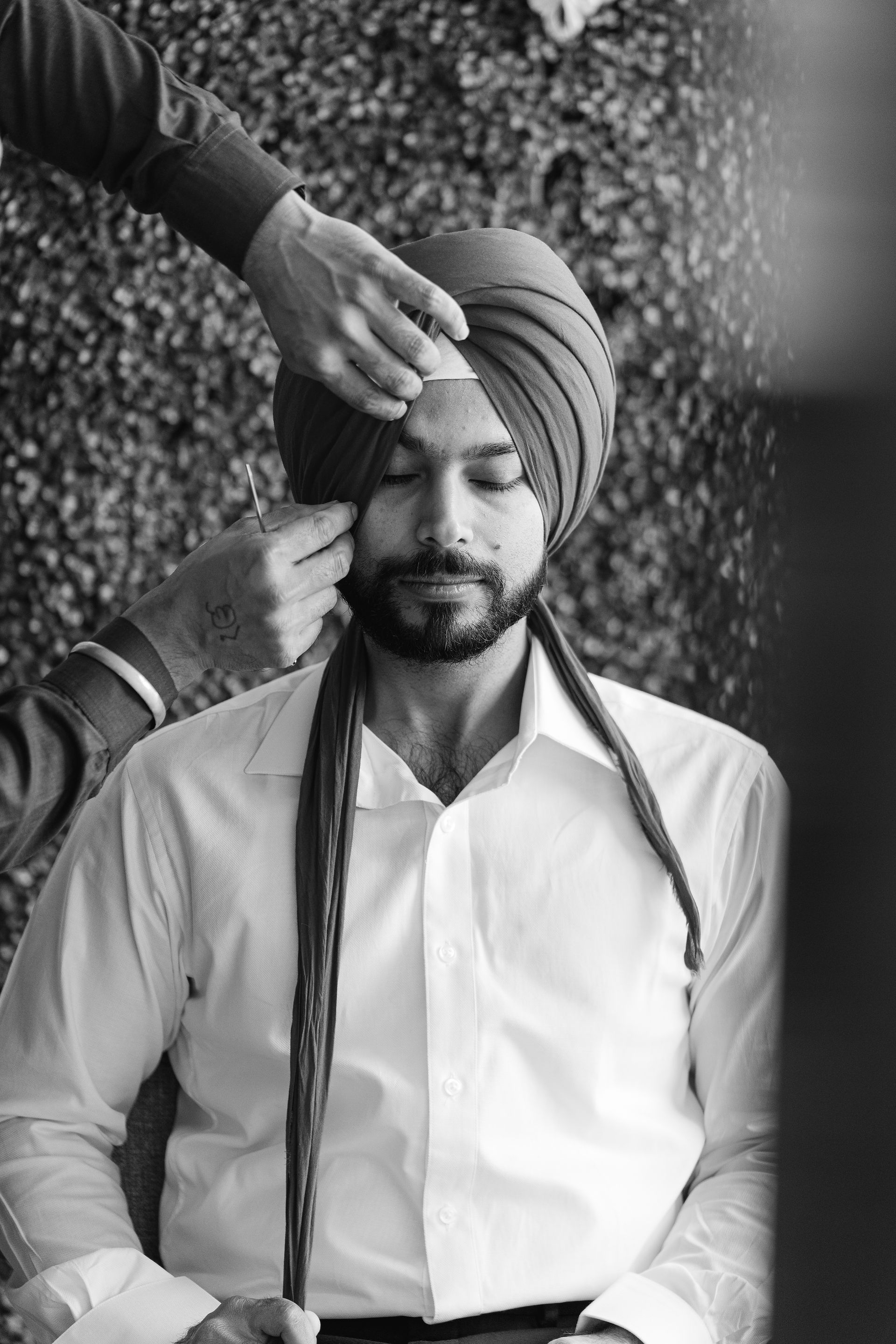 A meaningful moment of a Sikh groom having his turban tied by family, highlighting the authentic Sikh wedding traditions we specialize in capturing in Northern California.