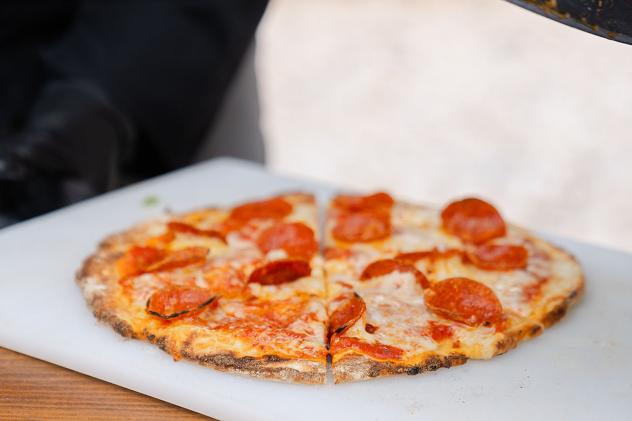 A close-up of a delicious pepperoni pizza sliced and ready to be served at an outdoor Zion National Park wedding reception.