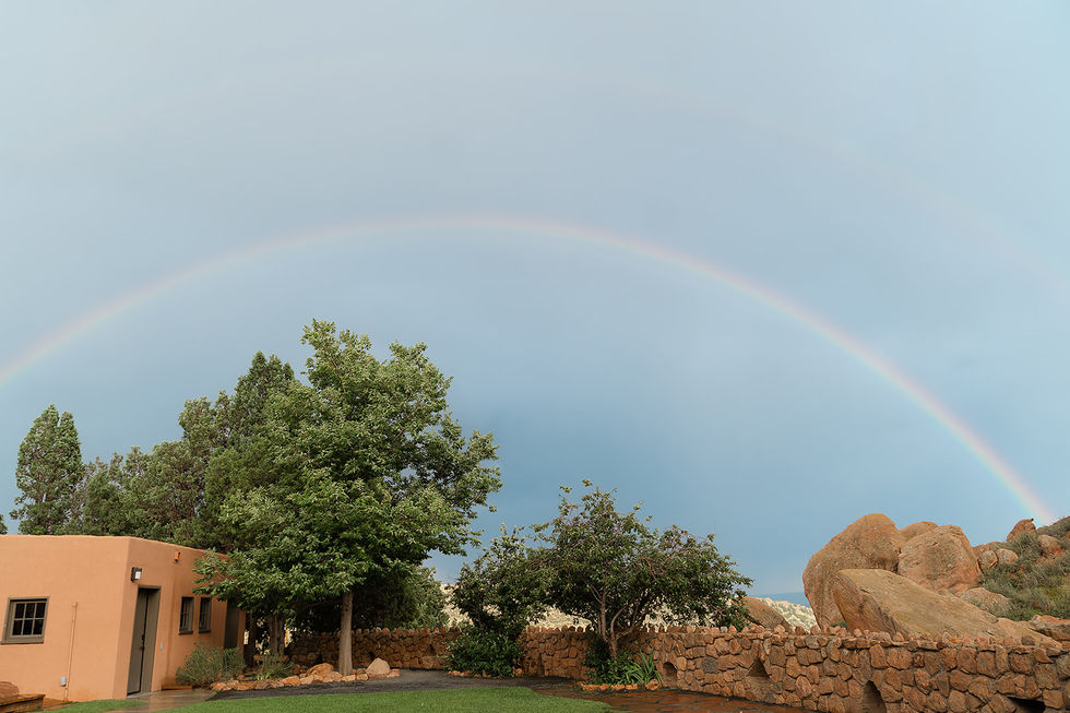 A vibrant rainbow over the red rock landscape and rustic buildings at the Colorado Trading Post wedding site.