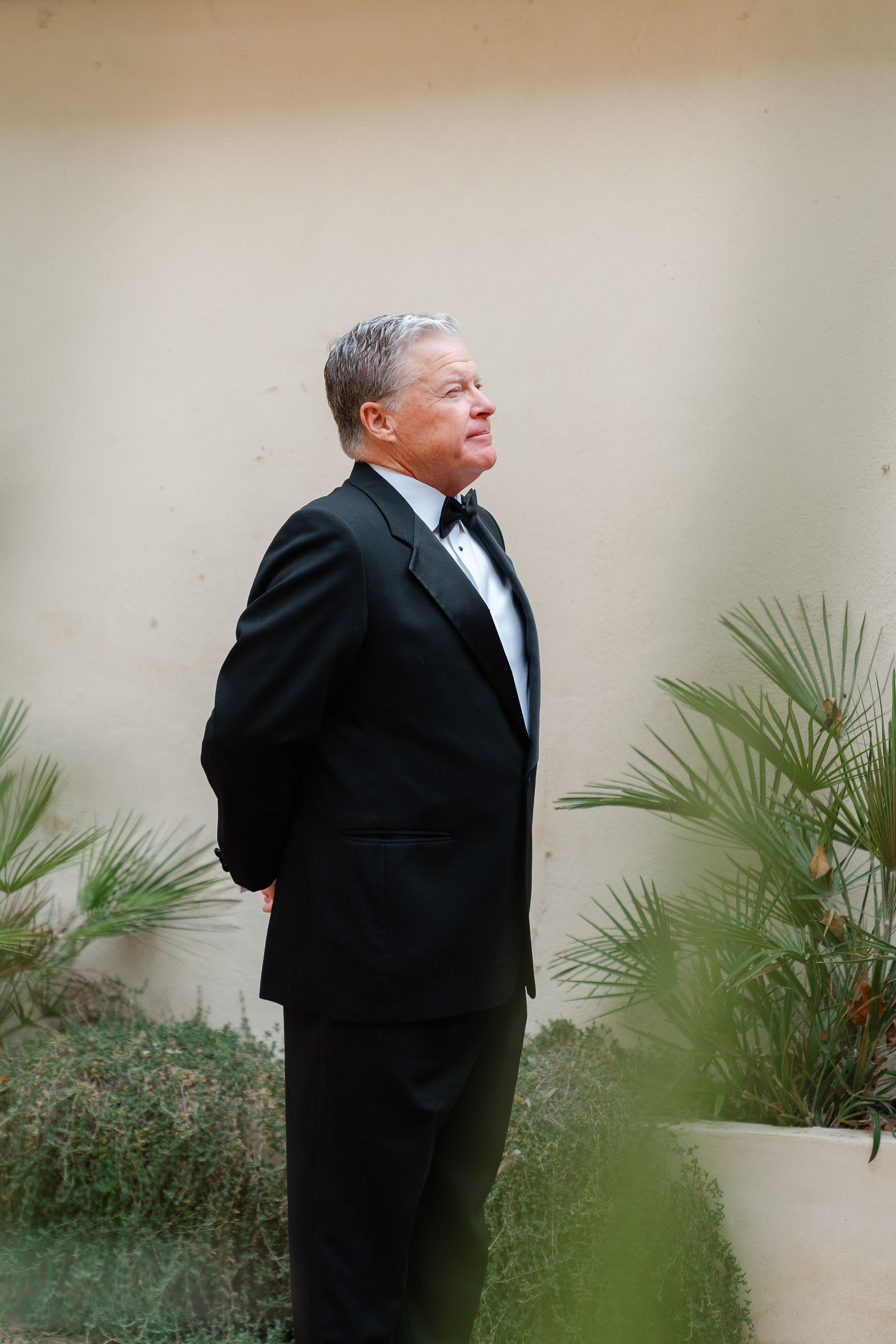 Father of the bride in a classic black tuxedo waiting emotionally for the first look at a destination wedding in Spain.