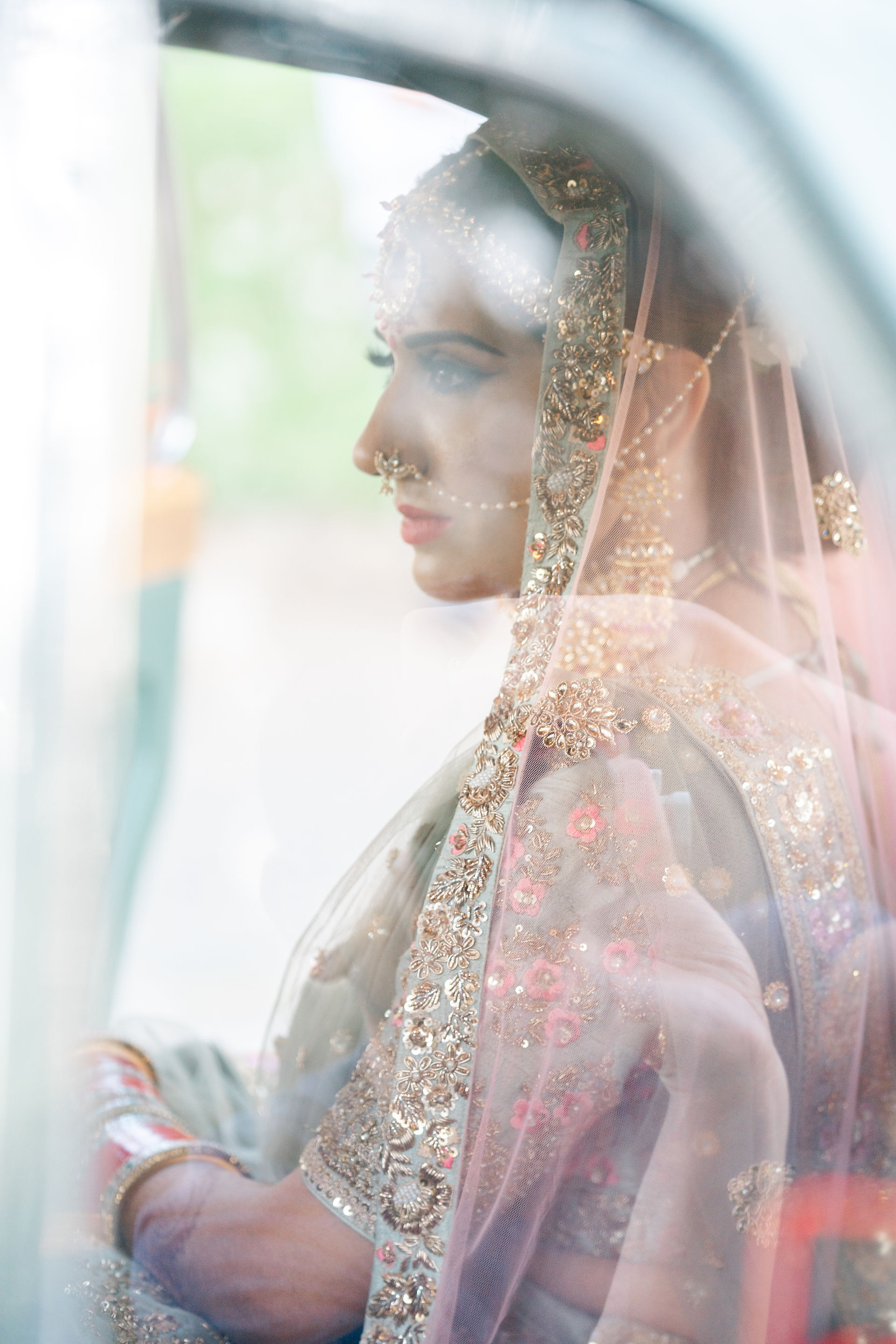A stunning profile portrait of a South Asian bride seated in a vintage car, highlighting her intricate bridal veil and jewelry at a Sacramento celebration.