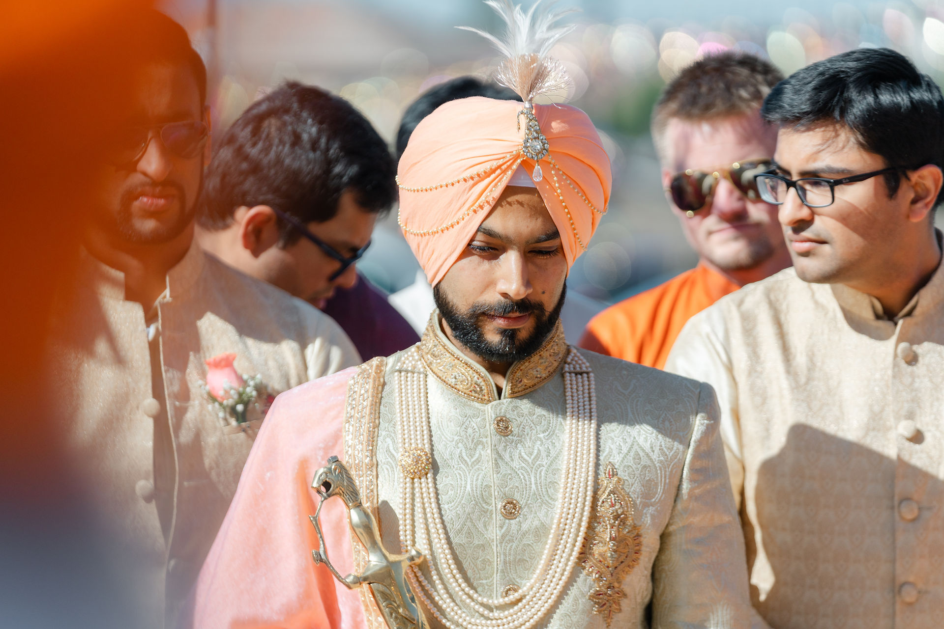 Cinematic close-up portrait of a Sikh groom wearing a traditional peach turban and intricate jewelry, capturing the elegant heritage of a Sacramento South Asian wedding.