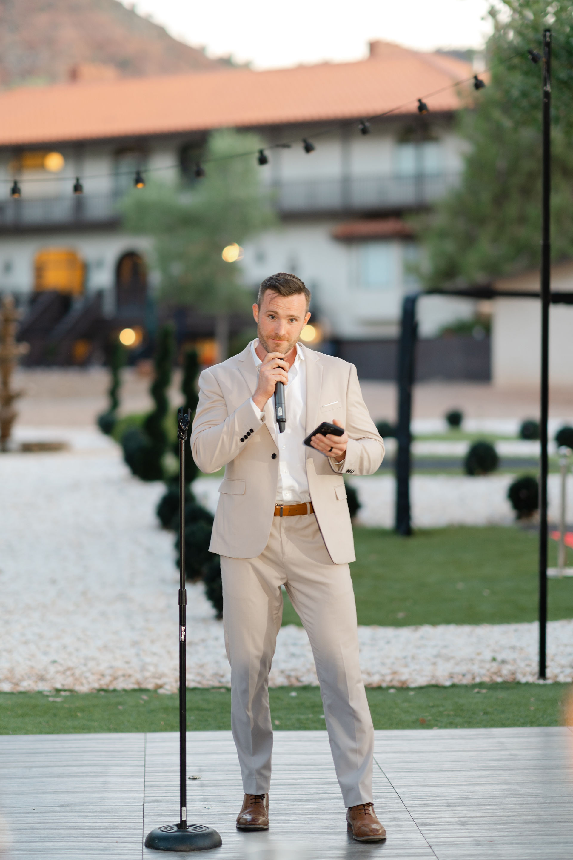 The groom, Thomas, giving a heartfelt speech into a microphone during the outdoor reception of his Zion National Park Wedding.
