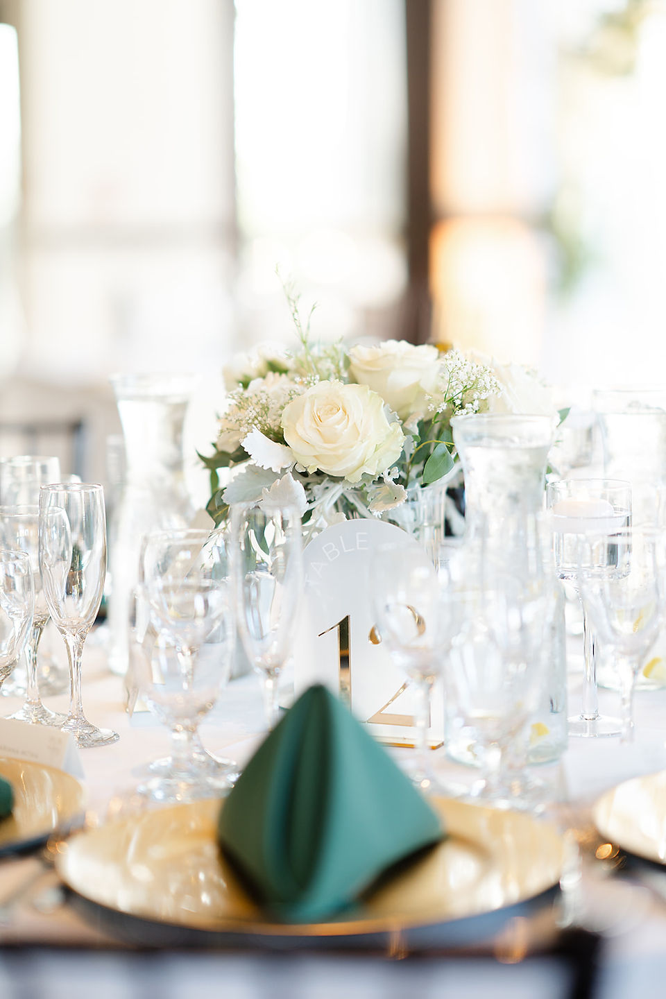 Sophisticated wedding table setting with a lush white floral centerpiece and glowing candles for an indoor Stone Tree Golf Club reception.