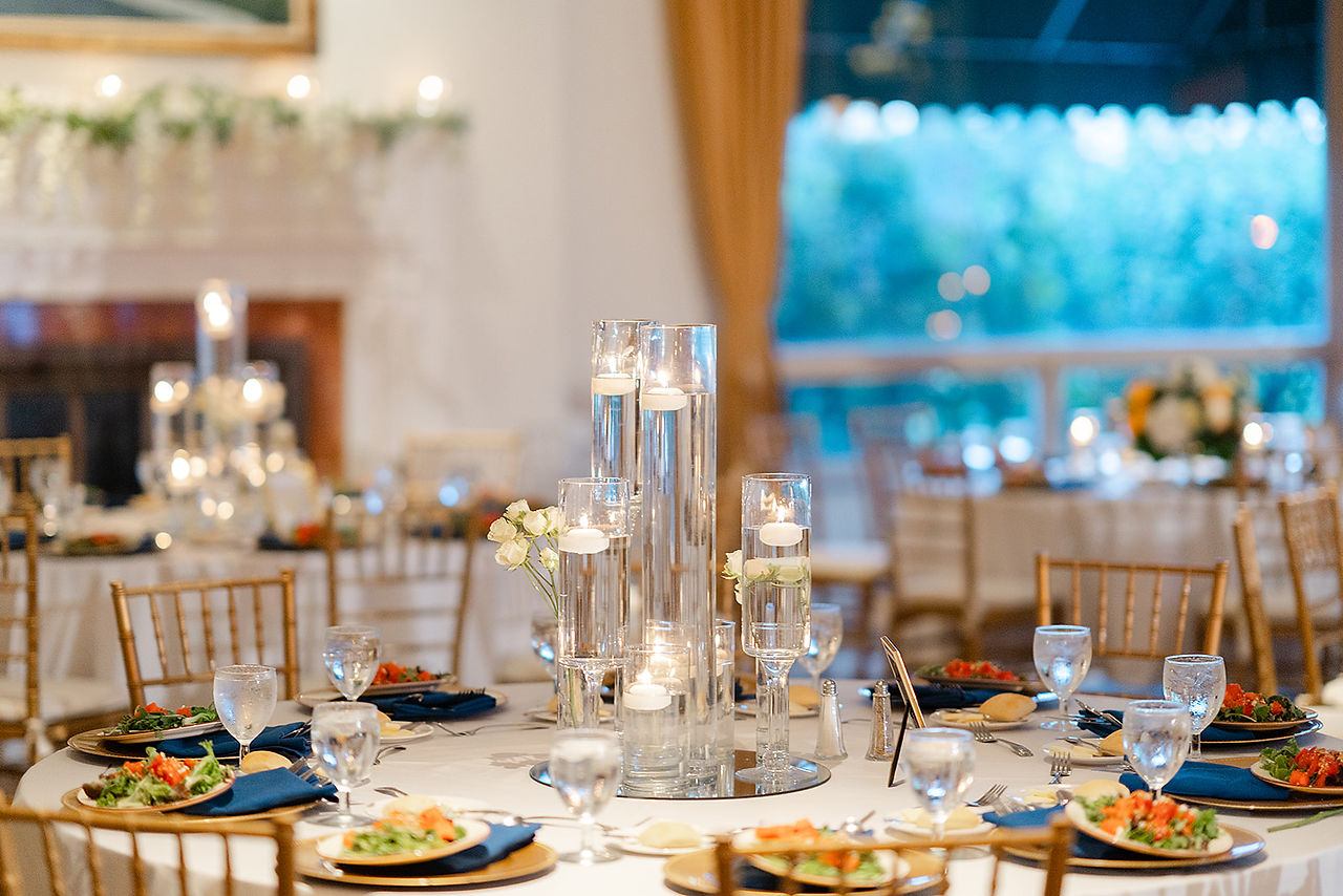 Elegant reception tablescape at Norwood Hills Country Club in St. Louis, featuring gold chairs, navy linens, and floating candle centerpieces, planned by Big Bow Events.