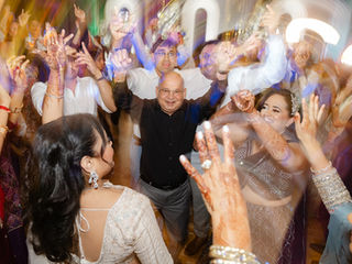 A high-energy Indian wedding reception finale with the groom and guests dancing to Bollywood music under professional event lighting.