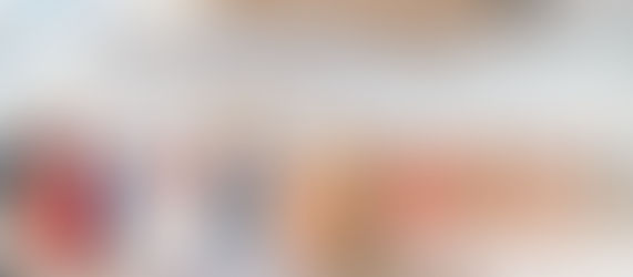 An Indian bride and groom standing at the mandap during a traditional Sikh wedding ceremony in a grand hall, surrounded by bridesmaids in pink lehengas and family.