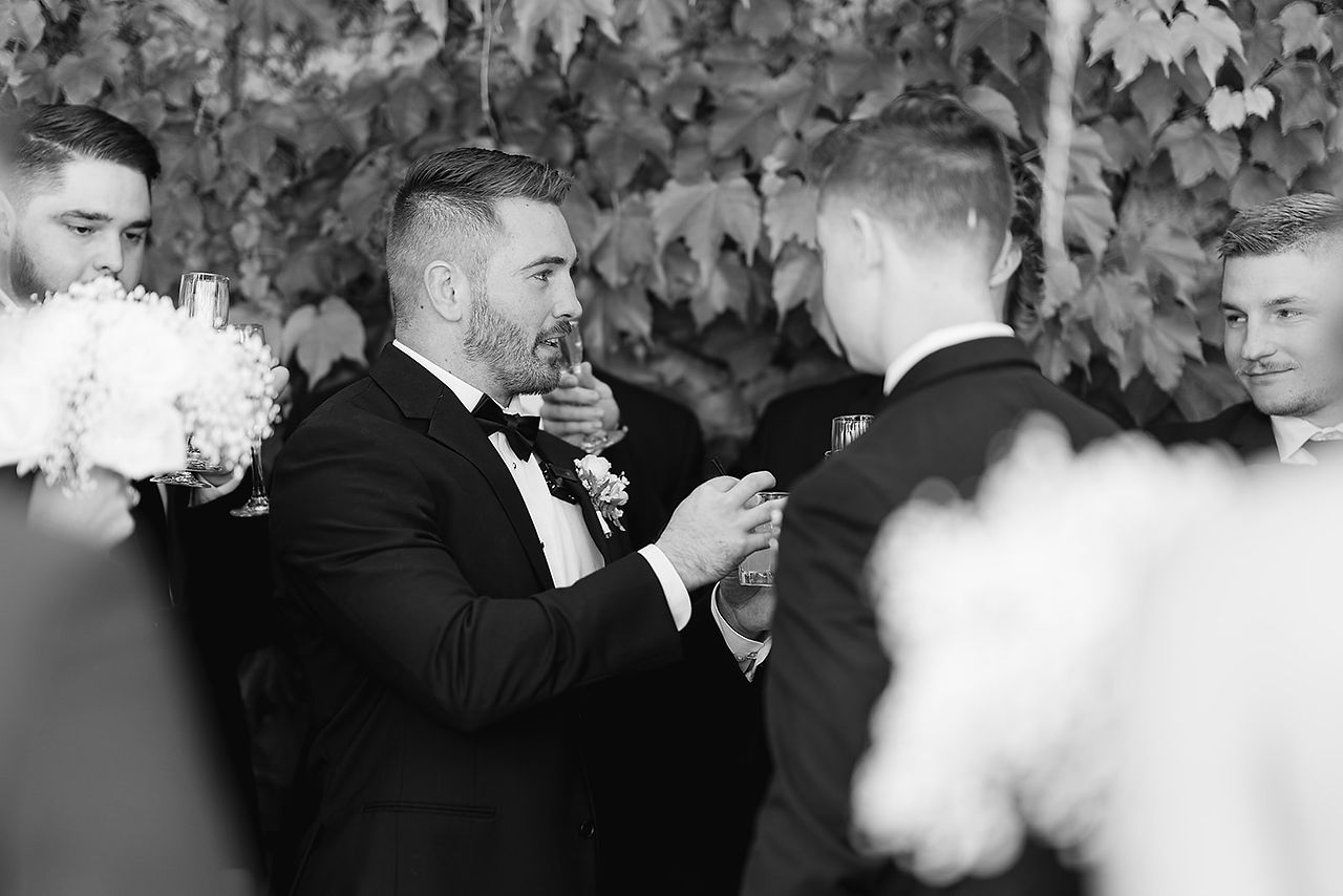 The groom and his groomsmen sharing a celebratory toast and laughing together before the Stone Tree Golf Club wedding reception.