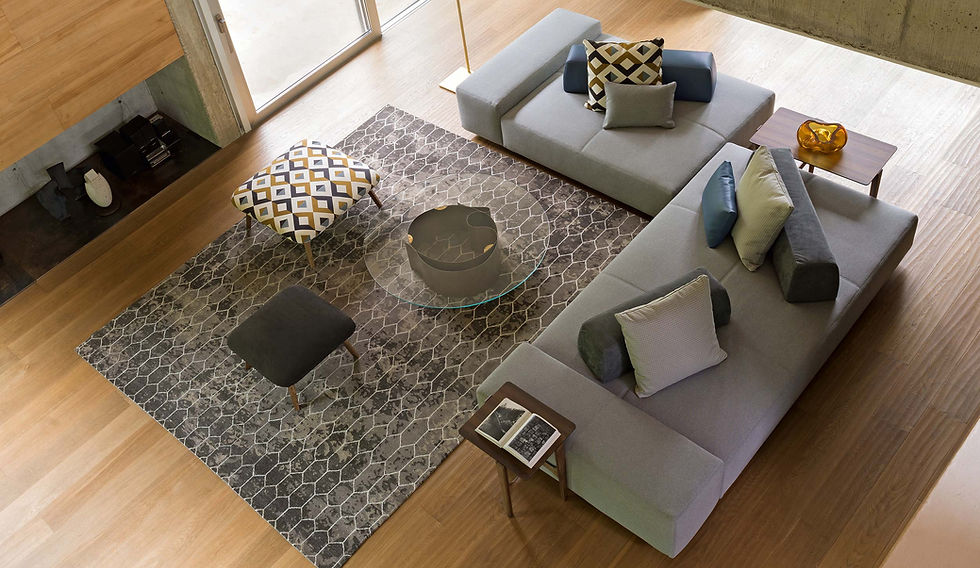 Canapés modulables gris clair avec coussins colorés sur tapis graphique dans salon contemporain.