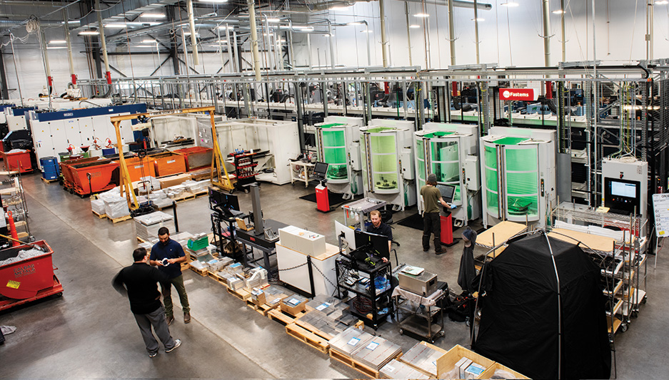 Operator‑assisted robotic CNC loading: Shows staff working alongside robot loaders