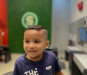 alt="Criança recebendo corte de cabelo moderno na barbearia Sport Cortes"