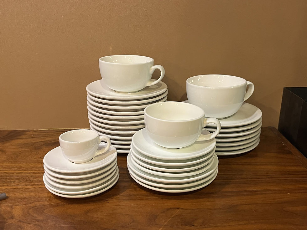 Stacks of small and big white ceramic mug and saucer sets.