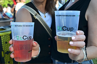 Reusable cups filled with beer in peoples hands.