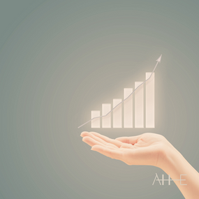 Hands hold a glowing upward bar graph on a muted green background. The text "AHUMAN EDGE" is in the bottom right corner.