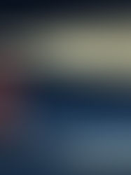 Red and white lighthouse shines a bright beam over dark ocean waters under a starry night sky, illuminating rocky surrounds.