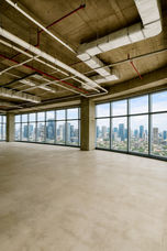 Spacious bare shell office floor in Altaire, Makati CBD, featuring open-plan layout, high ceilings, exposed structural columns, polished concrete flooring, and floor-to-ceiling windows with panoramic city views. Ideal for corporate offices, BPO setups, or flexible commercial workspace.