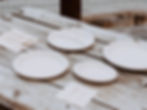 White biodegradable plates and wooden cutlery on a rustic wooden table, creating an eco-friendly outdoor dining setup. Showing free sample product options.