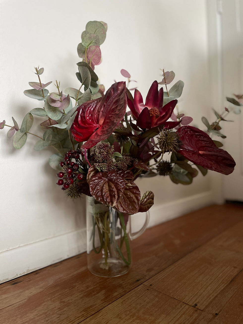 Side view of Burgundian bouquet featuring burgundy Anthuriums, Eucalyptus and Leucadendrons