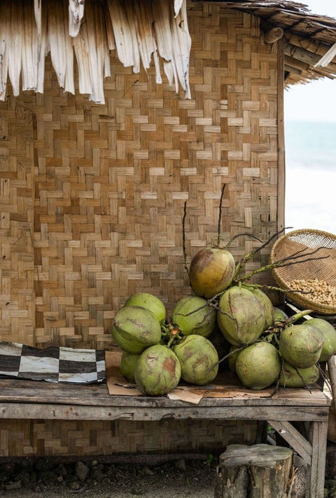 Fresh coconuts on wooden table beside tropical beach hut