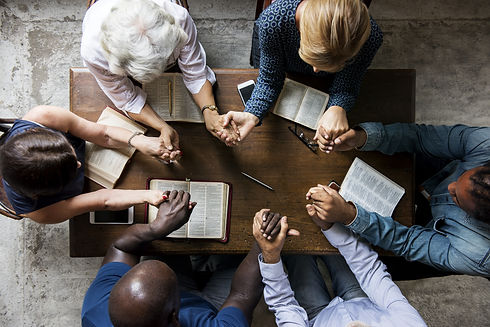 Group of people holding hands praying wo