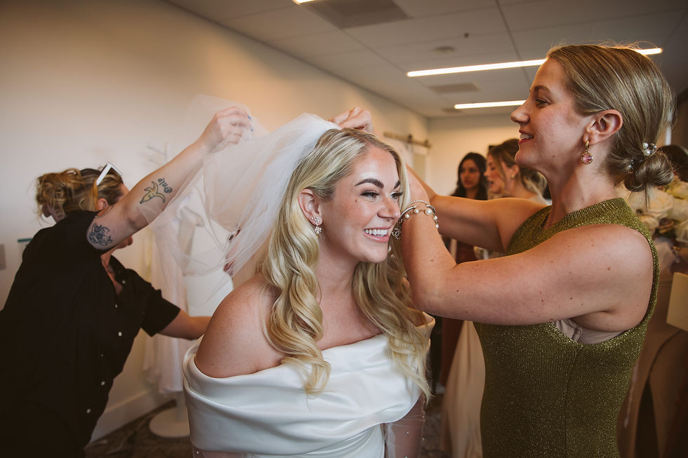 a bride is helped into her veil by a planner and her bridesmaids