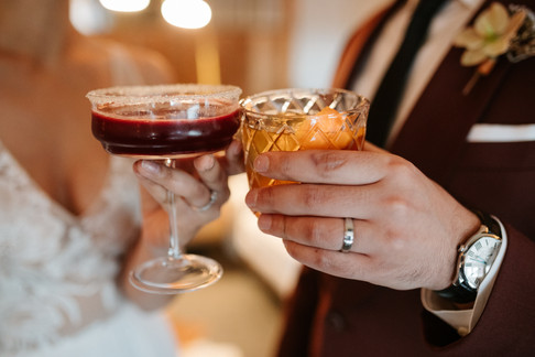 A bride and groom holding a Marionberry Lemon Drop and Barrel-Aged Maple Old Fashioned