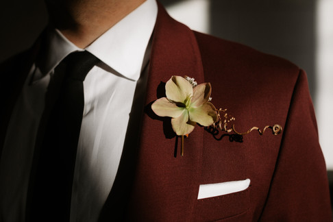 Natural wildflower boutonniere on maroon suit