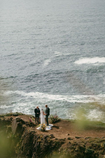 a faraway shot of an elopement on an ocean cliff