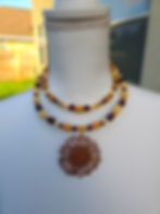 Beaded necklace with a sunflower pendant on a mannequin.