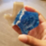 Hand holding a Texas-shaped resin art piece with blue waves.