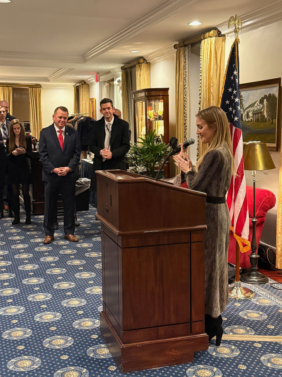Woman speaking at a podium with American flag