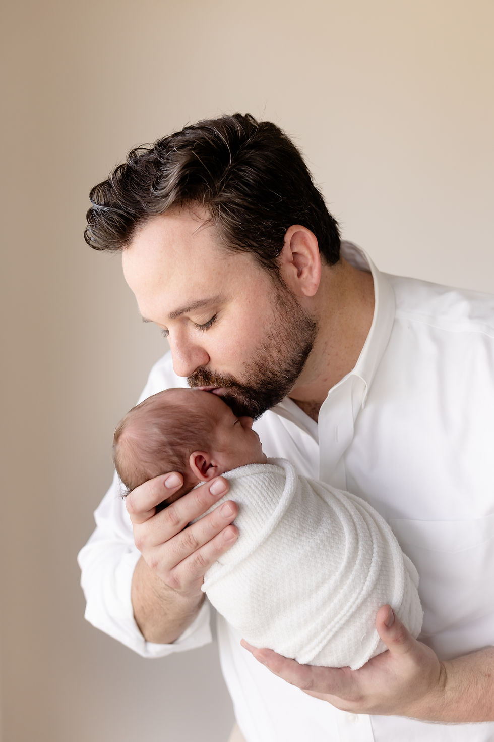 father kissing newborn baby
