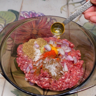 adding finely chopped onions and oil to lamb mince to make indian style lamb meatballs.