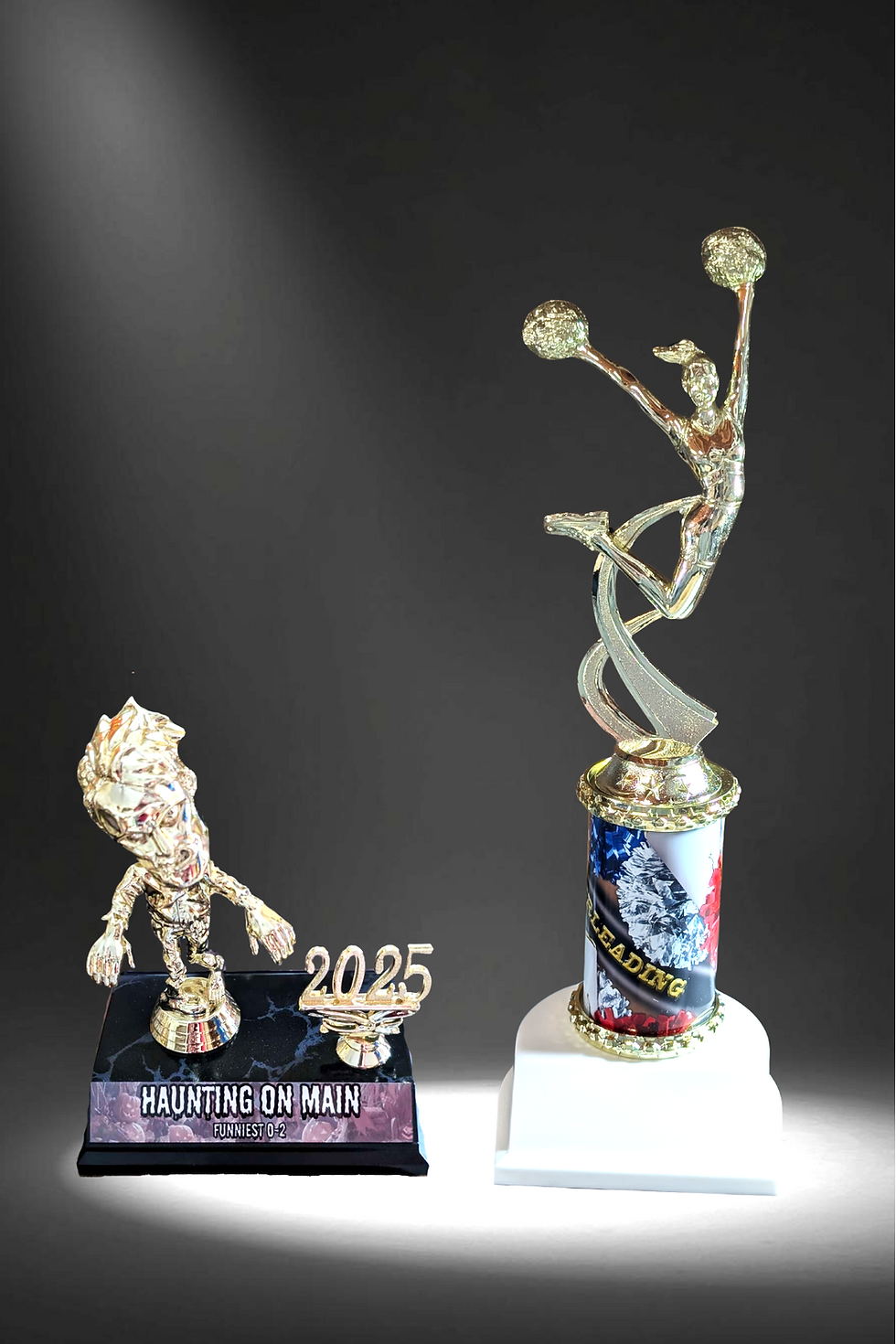 Trophies with text: Haunting on Main 2025 and Leading Cheerleader award. Trophies.