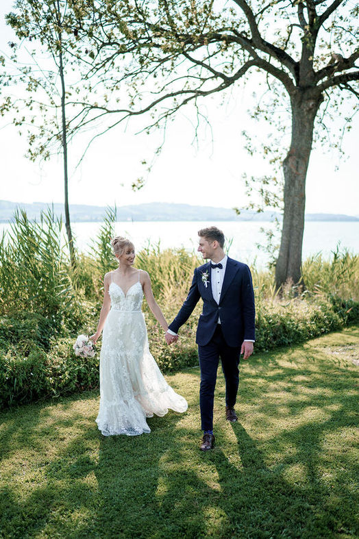 brautpaar läuft hand in hand auf einer wiese im freien direkt am ufer des zürichsees