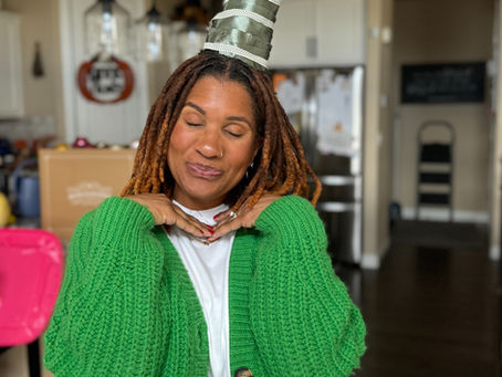 Woman wearing green cardigan with DIY holiday hair hat made from decorated Christmas tree frame with ornaments and star topper