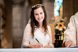 camille, souriante dans sa robe de mariée Lutilu réalisée en dentelle chantilly et crepe de soie